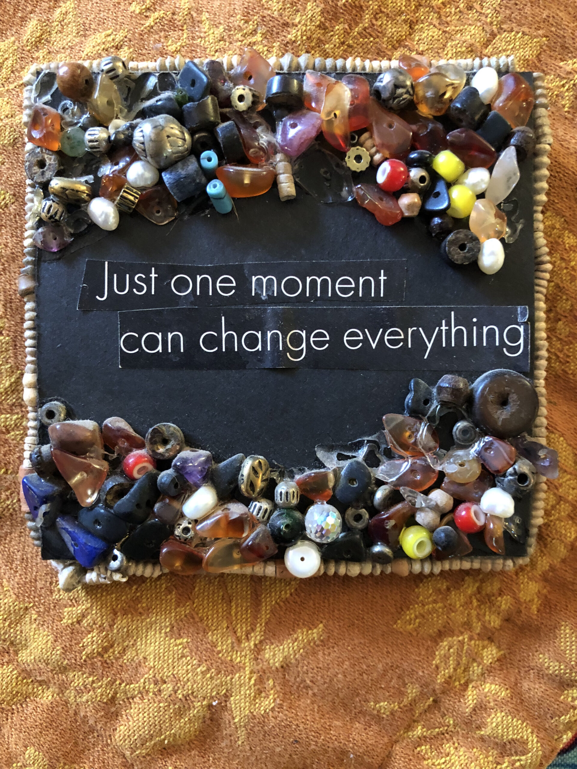 Hand made magnet with beads on top and bottom. White text with black background reads: Just one moment can change everything.