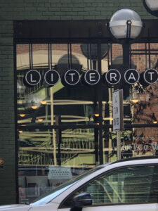 A store window with letters spelling out most of the name Literati. 