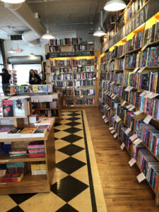 A black and white checkered floor in a long room lined with books. 