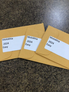 Tan seed packets with white labels reading "molokai" and "easy". 